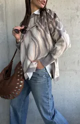 Sweater de punto con diseño abstracto de líneas orgánicas en tonos gris y beige, cuello redondo, manga larga con puños ajustados y corte holgado.