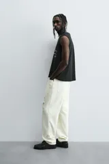 Camiseta sin mangas (tank top) negra, corte boxy fit, con cuello redondo y sisa con acabado irregular. Presenta un estampado frontal con texto manuscrito en verde y blanco que dice: "I look cool online, but offline I'm even better... Chase real likes!".