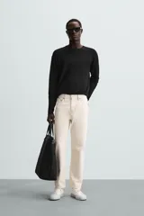 Jersey color crudo de tejido de punto, con cuello redondo y mangas largas. Corte amplio y terminaciones en rib.