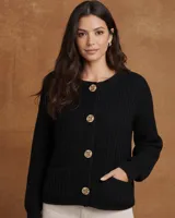 Saco de punto tejido con textura acanalada, color negro, de corte recto y manga larga. Presenta cierre frontal con botones dorados decorativos y bolsillos frontales funcionales.
