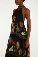 Vestido largo negro con cuello halter y diseño sin mangas, confeccionado en tejido liviano con estampado multicolor inspirado en elementos barrocos y tropicales.