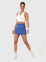 Falda deportiva azul con ribete blanco en la cintura, diseñada con calza interior incorporada que incluye bolsillo lateral.