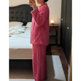 Conjunto de pijama de dos piezas confeccionado en plush suave con textura de ochos. Incluye una remera de manga larga con cuello redondo y un pantalón de corte recto con cintura elástica.