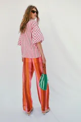 Camisa de corte oversize con estampado de rayas verticales rojas y blancas. Presenta cuello solapa, escote en pico y mangas largas abullonadas con puños elásticos.