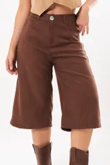 Bermuda de silueta amplia y tiro medio, color marrón chocolate, con bolsillos delanteros y traseros, cierre frontal con cremallera y botón.