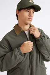 Campera Quiksilver modelo Milo para hombre, de color verde con textura en relieve y cuello camisero en contraste de color tostado. Cuenta con cierre frontal entero, bolsillos laterales ribeteados, puños y dobladillo inferior elásticos.