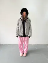 Campera reversible con cierre frontal. Un lado es de algodón negro con estampa y bordado en color rosa, y el otro lado es de tela polar de pelo largo en color gris. Presenta corte oversize, capucha y puños acanalados.
