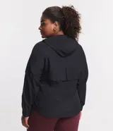Campera rompeviento deportiva de color negro, con cierre frontal de cremallera, capucha ajustable con cordón, bolsillos laterales y ruedo elástico. Presenta recortes delanteros y diseño de manga larga.