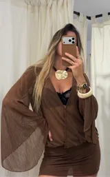 Vestido corto color marrón de tejido translúcido con textura, escote en V profundo y mangas largas acampanadas. Presenta un diseño ajustado en la parte inferior con frunces laterales.