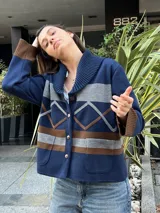 Campera de punto azul marino, con cuello smoking acanalado, bolsillos frontales aplicados y cierre de botones. Presenta bandas horizontales grises y marrones, y detalles geométricos en el frente.