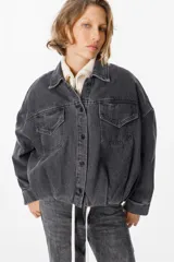 Chaqueta de jean color gris lavado, con corte oversize, mangas amplias y bolsillos frontales con solapa. Presenta cierre frontal con botones metálicos y cuello clásico.