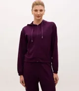 Campera deportiva de corte regular, color violeta, confeccionada en tejido modal. Presenta cuello con capucha, cordón ajustable, cierre frontal por cremallera, mangas largas con puños ajustados y bolsillos laterales.