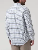 Camisa de manga larga RKF confeccionada en franela de algodón orgánico, con diseño de cuadros en tonos celestes, azules y grises sobre base blanca. Presenta cuello con botones, cierre frontal abotonado y bolsillo en el pecho con logo bordado.