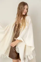 Ruana de lana color beige, tejida en punto acanalado con terminación de flecos en los bordes.