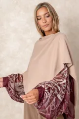 Poncho de tejido de punto color beige con diseño de capa, que deja al descubierto mangas amplias de gasa estampada en tonos bordó y violeta con motivos de cadenas.