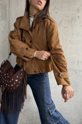 Campera tipo bomber de gamuza color camel, con diseño de doble botonadura frontal, cuello camisero y mangas largas con puños abotonados.