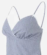 Pijama short doll de dos piezas confeccionado en algodón, con estampa de cuadros vichy en tonos azul y blanco. La musculosa presenta breteles finos, escote corazón con delicado encaje blanco y silueta fluida. El short cuenta con cintura elástica, pequeño moño frontal y terminación ondulada en el ruedo.