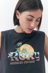 Musculosa Roxy modelo Line Up de color negro, con diseño sin mangas, cuello redondo y corte corto. Cuenta con un estampado frontal gráfico estilo vintage que incluye la palabra "Roxy", palmeras y un sol, acompañado del texto "sunsets chaser".