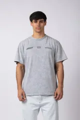 Remera de algodón con efecto de lavado snow-wash en color gris. Presenta un diseño de cuello redondo, mangas cortas y un estampado frontal minimalista con gráficos de estilo automovilístico y cuadros de meta.