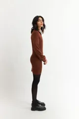 Vestido corto negro de tejido de punto acanalado, con mangas largas y medio cierre frontal.