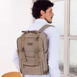 Mochila matera y porta notebook en tela canvas de color marrón, con diseño versátil, correas ajustables, bolsillos frontales con cierre y asas superiores de mano.