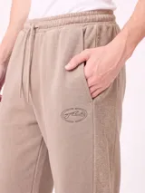 Pantalón jogger holgado de color gris con efecto acid wash y franjas laterales negras. Cuenta con cintura elástica con cordón ajustable y bolsillos laterales.