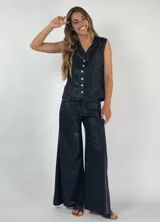 Pantalón metalizado color negro, de corte palazzo, tiro alto y cierre frontal.