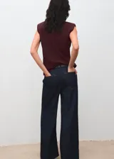 Blusa de color bordó con cuello barco, hombreras marcadas y diseño recto sin mangas.