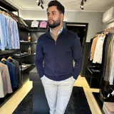 Campera tejida azul marino con cierre frontal, cuello alto y bolsillos laterales.