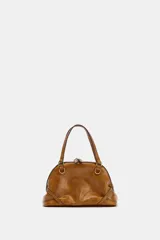 Bolso mini tipo bandolera de color tostado con acabado efecto cuero envejecido. Cuenta con asas de mano fijas, herrajes metálicos dorados, bolsillo interior con cierre y cremallera superior.