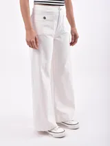 Pantalón de jean blanco roto (off white) de tiro alto y corte ancho (wide leg). Presenta bolsillos cargo grandes con tapa y botón metálico en la parte delantera de los muslos.