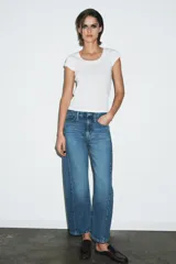 Jeans de tiro medio con corte relajado y largo al tobillo. Presenta diseño de cinco bolsillos, trabillas en la cintura y cierre frontal con cremallera y botón metálico.