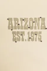 Musculosa de algodón con cuello redondo y diseño sin mangas. Presenta un estampado frontal con el texto Arizona Est. 1975 y detalle de tachas metálicas decorativas en el escote y las sisas.