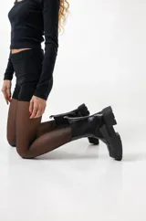 Borcegos negros de cuero sintético con suela track y elásticos laterales.