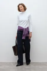 Remera de cuello alto y manga larga, confeccionada en tejido liso, con detalle de puntilla delicada en los puños.
