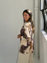 Sweater de punto con estampado animal print tipo vaca en tonos camel y marrón, de corte holgado, escote en V y mangas tres cuartos con dobladillo.