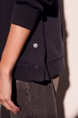 Sweater con capucha color negro, con cordones ajustables y botones en el escote.