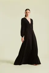 Vestido midi negro con escote en V profundo y botones dorados frontales. Presenta mangas largas abullonadas, corte en la cintura y falda fluida.