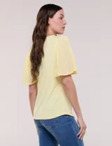 Blusa blanca de silueta suelta con escote redondo y mangas cortas estilo mariposa confeccionadas en tela plisada translúcida.