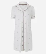 Camisón corto color blanco marfil con estampa floral sutil, cuello solapa, mangas cortas y cierre frontal con botones. Cuenta con ribetes en contraste en cuello y puños.
