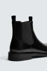 Bota estilo Chelsea de piel negra con elásticos laterales y suela con ligero tacón.