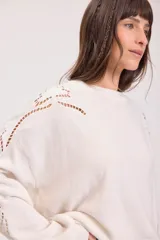 Sweater de punto color negro, de corte holgado y manga larga, con detalle de bordado calado en los hombros y a lo largo de las mangas.