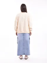 Buzo de cuello redondo y manga larga, color marrón, con estampado gráfico frontal en color lila que incluye texto y personajes animados.