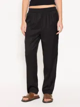 Pantalón negro de sarga, con elástico en la cintura, bolsillos laterales y ojal en la espalda.