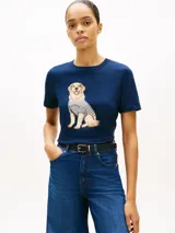 Remera de manga corta azul marino con cuello redondo, confeccionada en algodón. Presenta un diseño gráfico bordado en el pecho de un perro Golden Retriever vestido con una camiseta a rayas.