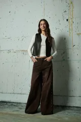 Jean de corte wide leg en color gris lavado, con diseño de aberturas laterales decoradas con tachas metálicas a lo largo de toda la pierna.