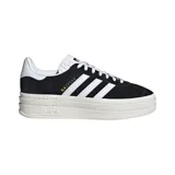 Championes adidas modelo Gazelle Bold, de diseño clásico con plataforma triple. Confeccionados en gamuza negra con las tres tiras laterales y refuerzo en el talón en color blanco. Incluye el nombre del modelo en letras doradas en el lateral y suela de plataforma de goma en tono crema.