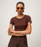 Blusa marrón de algodón en tejido de malla, con mangas cortas y cuello redondo. Presenta detalles ondulados en tono contrastante en el cuello y en los bordes de las mangas.