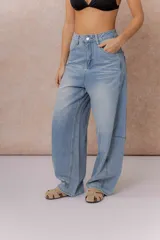 Jean de tiro alto con silueta balloon oversize, confeccionado en denim rígido de lavado celeste desgastado. Presenta costuras curvas que aportan volumen, cierre y botón frontal, y bolsillos funcionales.