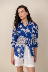 Camisa azul con estampado floral en tono blanco, de manga larga, cuello camisero y cierre frontal de botones.